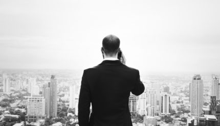 business man talking on phone, looking at city