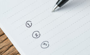 To-do list or writing tasks priority concept, close-up of list on numbers with pen and headline as To Do List on white paper notepad on wood table.